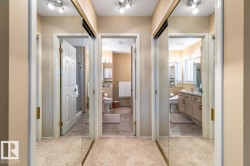 Hallway featuring mirrored sliding closet doors with track lighting - 