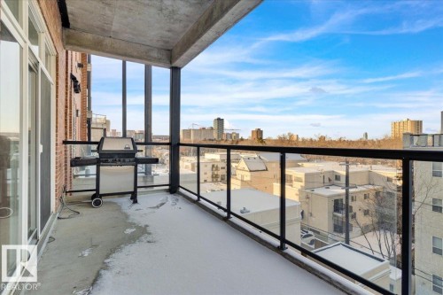 Balcony featuring a concrete floor, glass and black metal railing, and a brick exterior wall - 406 10728 82 Avenue, Edmonton, AB - Outdoor With Balcony With View With Exterior