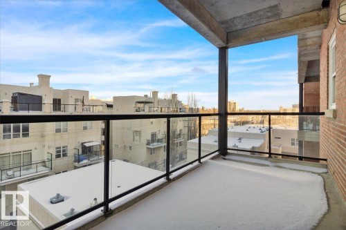 Outdoor balcony featuring concrete flooring, black metal and glass railing, and a red brick exterior wall - 406 10728 82 Avenue, Edmonton, AB - Outdoor With Balcony With View With Exterior