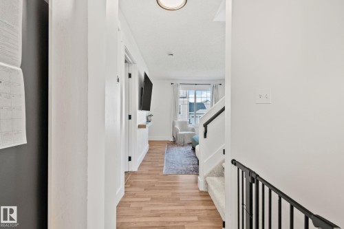 Hallway featuring wood-finish flooring, white walls, and a built-in wall shelf - 53 2503 24 Street, Edmonton, AB - Indoor Photo Showing Other Room