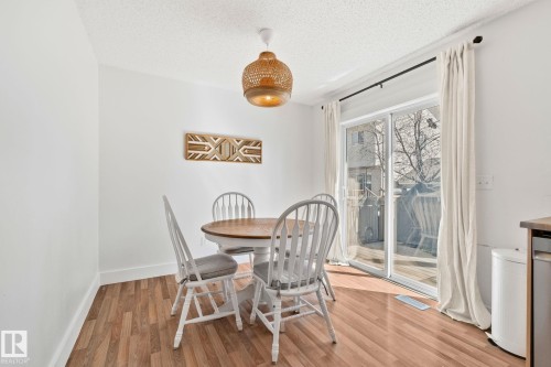 Dining area featuring wood-finish flooring, a contemporary woven pendant light fixture, and white walls - 53 2503 24 Street, Edmonton, AB - Indoor Photo Showing Dining Room
