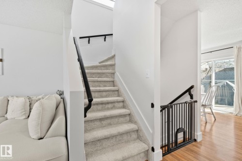 Carpeted staircase with black handrails and white risers - 53 2503 24 Street, Edmonton, AB - Indoor Photo Showing Other Room