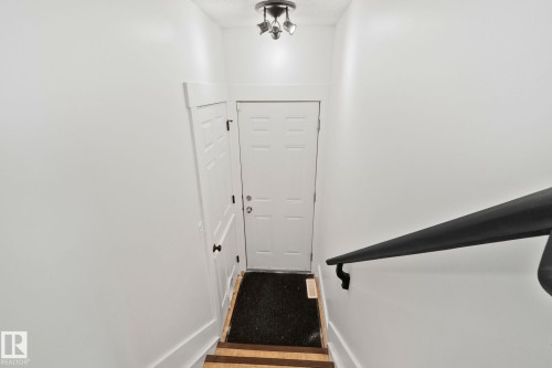 Stairwell featuring wood-finish treads, a black handrail, and white walls - 53 2503 24 Street, Edmonton, AB - Indoor Photo Showing Other Room