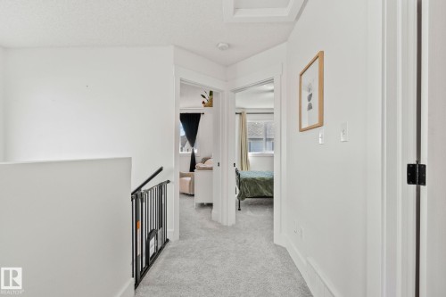 Carpeted hallway featuring white walls, white trim, and white doors with black hardware - 53 2503 24 Street, Edmonton, AB - Indoor Photo Showing Other Room