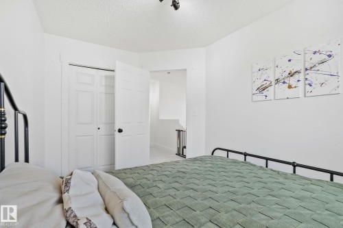 Room featuring white walls, a textured ceiling, a bi-fold closet with panel doors, and an additional white panel door - 53 2503 24 Street, Edmonton, AB - Indoor Photo Showing Bedroom