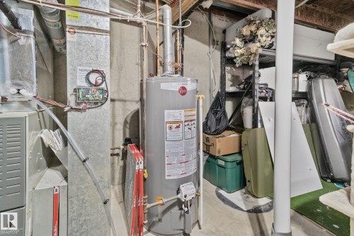 Rheem water heater unit, galvanized ductwork, concrete flooring, and exposed ceiling joists - 53 2503 24 Street, Edmonton, AB - Indoor Photo Showing Basement
