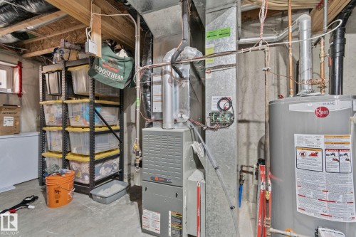 Utility area featuring a Rheem water heater and a Rheem furnace, exposed ductwork, concrete flooring, and an unfinished ceiling - 53 2503 24 Street, Edmonton, AB - Indoor Photo Showing Basement