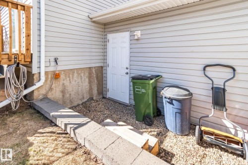 Light-colored horizontal siding exterior featuring a white door, concrete foundation, and gravel ground cover - 53 2503 24 Street, Edmonton, AB - Outdoor With Exterior