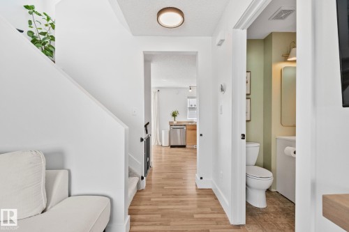 Hallway featuring wood-finish flooring, a recessed ceiling light, and a staircase with a white railing - 53 2503 24 Street, Edmonton, AB - Indoor Photo Showing Bathroom