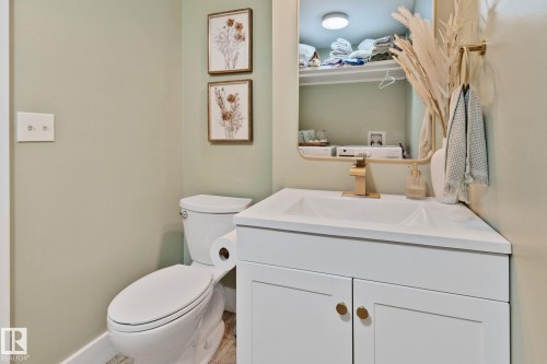 Corner vanity with an integrated white sink, gold-tone faucet, and white cabinet storage featuring gold-tone hardware - 53 2503 24 Street, Edmonton, AB - Indoor