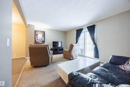 The living area features carpeting and neutral-toned walls, with a sliding glass door providing access to an exterior space - Sherwood Park, AB - Indoor