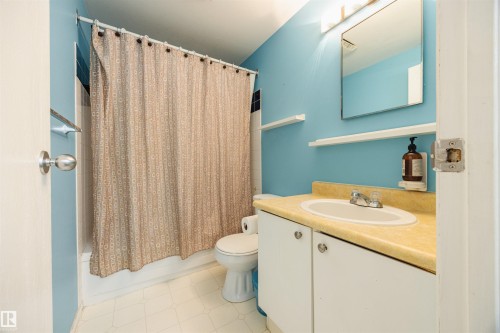 Bathroom featuring a vanity with a countertop and an integrated sink, a toilet, and a shower area with a shower curtain - Sherwood Park, AB - Indoor Photo Showing Bathroom