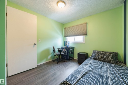 Bedroom featuring light green walls, a window with blinds, and dark-toned flooring - Sherwood Park, AB - Indoor Photo Showing Bedroom