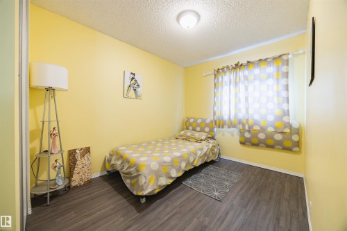 This room features light yellow walls and dark wood-style flooring - Sherwood Park, AB - Indoor Photo Showing Bedroom