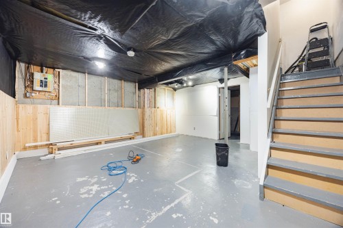 The property features a spacious room with partially finished walls, a concrete floor, and a staircase with painted treads - Sherwood Park, AB - Indoor