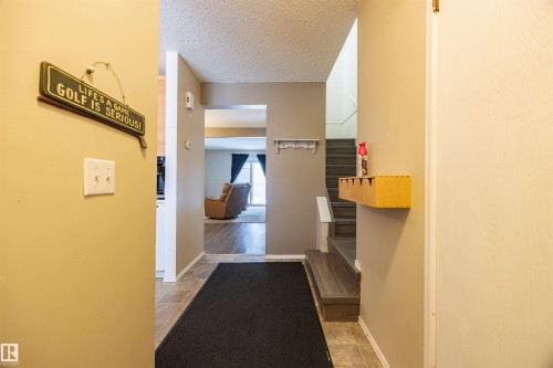 The property features a warm entryway with tile flooring and a view into a living space with wood-look flooring - Sherwood Park, AB - Indoor Photo Showing Other Room