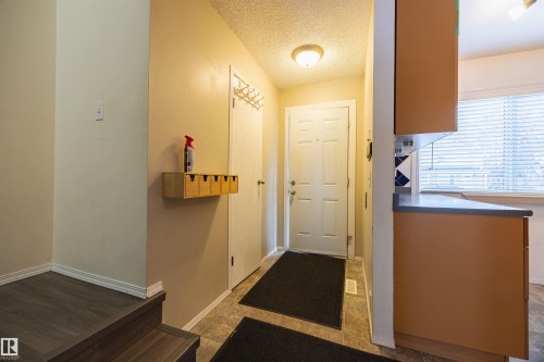 The entry area features a white door, tiled flooring, and a wall-mounted light fixture - Sherwood Park, AB - Indoor Photo Showing Other Room