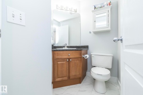 Bathroom featuring a wood-finish vanity with a dark countertop and undermount sink, a wall-mounted mirror, and tile flooring - 65 Birchmont Drive, Leduc, AB - Indoor Photo Showing Bathroom