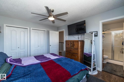 Bedroom featuring a ceiling fan, dual bi-fold closet doors, and wood-finish flooring - 65 Birchmont Drive, Leduc, AB - Indoor Photo Showing Bedroom