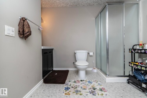 Bathroom featuring a glass-enclosed shower, white toilet, and dark wood-finish vanity - 65 Birchmont Drive, Leduc, AB - Indoor Photo Showing Bathroom