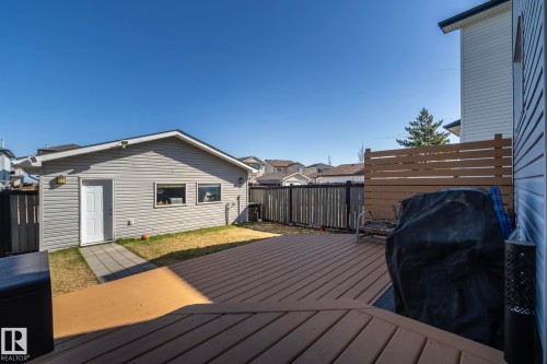 Spacious backyard featuring a composite deck, a separate garage structure with horizontal siding, and a paved pathway - 65 Birchmont Drive, Leduc, AB - Outdoor With Exterior