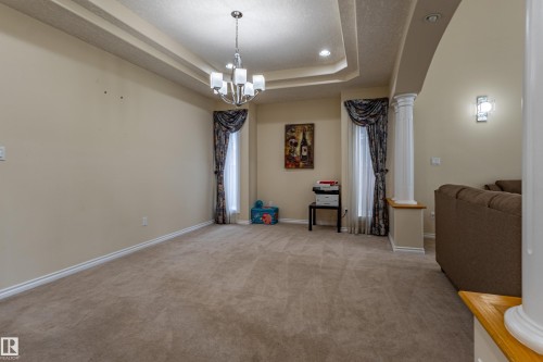 Tray ceiling with recessed lighting and a chandelier, neutral wall paint, carpet flooring, and decorative column - 195 Kulawy Drive, Edmonton, AB - Indoor Photo Showing Other Room