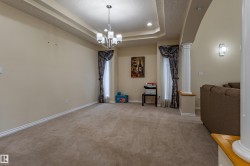 Tray ceiling with recessed lighting and a chandelier, neutral wall paint, carpet flooring, and decorative column - 