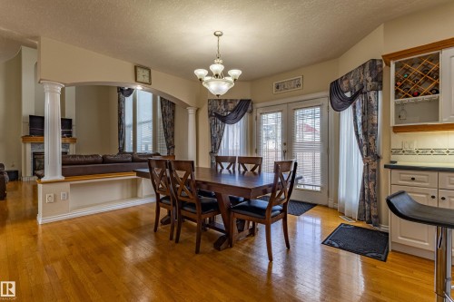 Dining area featuring hardwood flooring, an arched entryway with decorative columns, a built-in wine rack, and direct access to an outdoor space via double glass doors - 195 Kulawy Drive, Edmonton, AB - Indoor Photo Showing Dining Room