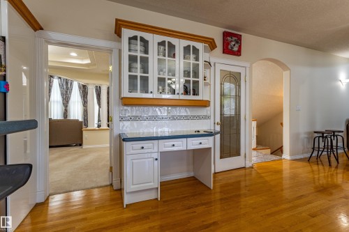 Built-in white cabinetry with glass display fronts, integrated desk space, and a tiled backsplash - 195 Kulawy Drive, Edmonton, AB - Indoor