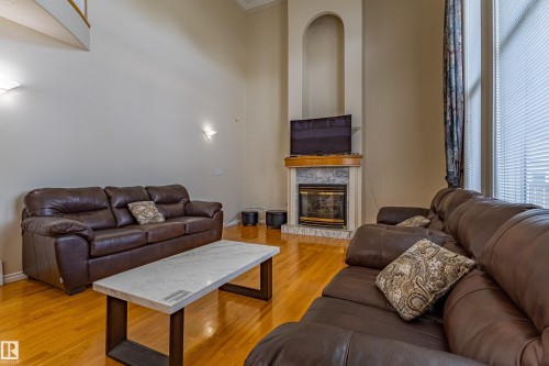 Living area featuring high ceilings, wood-finish flooring, and a fireplace with a marble-look surround and wood mantel - 195 Kulawy Drive, Edmonton, AB - Indoor Photo Showing Living Room With Fireplace