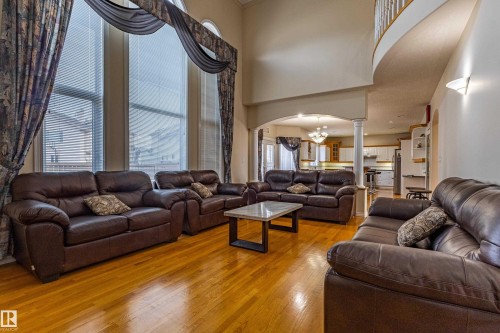 Two-story living area featuring tall windows with arch details, wood-finish flooring, and a curved second-story railing - 195 Kulawy Drive, Edmonton, AB - Indoor Photo Showing Living Room