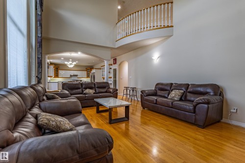 Two-story living area featuring wood-finish flooring, high ceilings, and an arched entryway - 195 Kulawy Drive, Edmonton, AB - Indoor Photo Showing Living Room