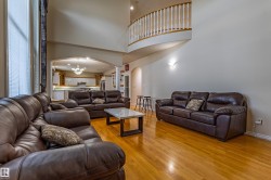 Two-story living area featuring wood-finish flooring, high ceilings, and an arched entryway - 