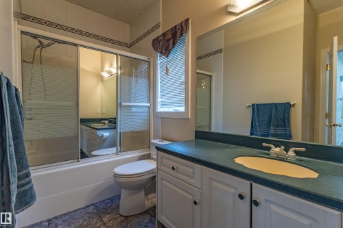 Bathroom featuring a built-in vanity with a countertop sink, a full mirror, and a shower-over-tub with glass enclosure - 195 Kulawy Drive, Edmonton, AB - Indoor Photo Showing Bathroom