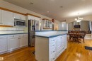 Kitchen featuring white cabinetry, a central island, stainless steel appliances, wood-finish flooring, and a decorative tile backsplash - 195 Kulawy Drive, Edmonton, AB  - Indoor Photo Showing Kitchen 