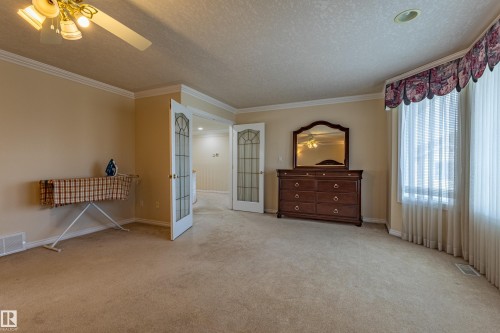 Carpeted room with a bay window, crown molding, and two sets of French doors - 195 Kulawy Drive, Edmonton, AB - Indoor