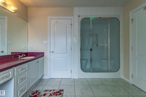 Bathroom featuring a vanity with a red countertop and an integrated sink, framed by a large mirror - 195 Kulawy Drive, Edmonton, AB - Indoor Photo Showing Bathroom