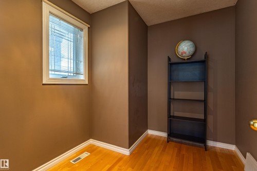 Warm-toned interior room featuring wood-finish flooring, white baseboards, and a window with blinds - 195 Kulawy Drive, Edmonton, AB - Indoor Photo Showing Other Room