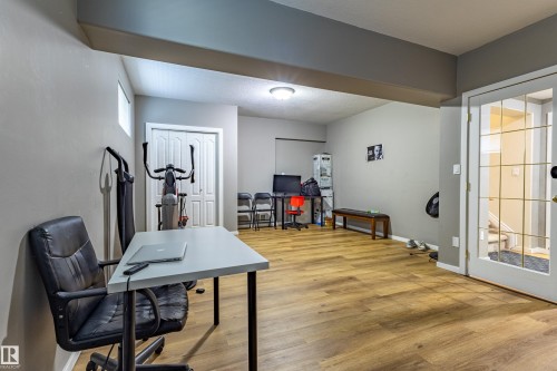 Spacious room featuring wood-finish flooring, light grey wall tones, and a white bi-fold closet door - 195 Kulawy Drive, Edmonton, AB - Indoor