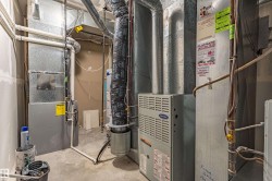 Utility area featuring a Carrier HVAC unit, water heater, and extensive ductwork - 