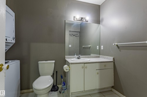 Bathroom featuring a stacked washer and dryer, a vanity with an integrated sink and countertop, a wall-mounted mirror, overhead lighting, and tiled flooring - 195 Kulawy Drive, Edmonton, AB - Indoor Photo Showing Bathroom
