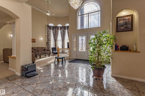 Grand foyer featuring polished tile flooring, double-door entry with decorative glass, a large arched window, vaulted ceilings, and an arched wall niche - 195 Kulawy Drive, Edmonton, AB - Indoor Photo Showing Other Room