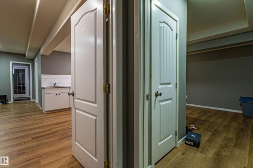 Interior hallway with wood-finish flooring and two paneled doors featuring brushed nickel hardware - 195 Kulawy Drive, Edmonton, AB - Indoor