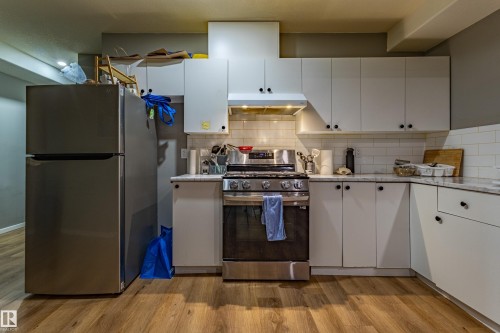 Kitchen featuring white cabinetry, subway tile backsplash, stainless steel range with overhead ventilation, and light-toned wood-finish flooring - 195 Kulawy Drive, Edmonton, AB - Indoor Photo Showing Kitchen