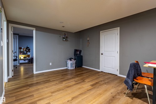 Spacious room featuring wood-finish flooring, two panel doors with hardware, white baseboards, and neutral wall paint - 195 Kulawy Drive, Edmonton, AB - Indoor