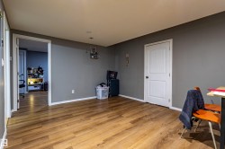 Spacious room featuring wood-finish flooring, two panel doors with hardware, white baseboards, and neutral wall paint - 