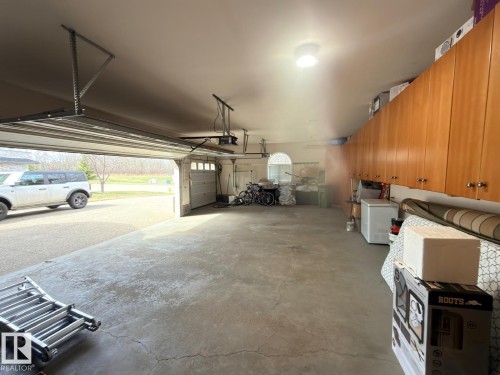 Spacious garage featuring concrete flooring, a large overhead door, and extensive built-in wooden cabinetry for storage - 195 Kulawy Drive, Edmonton, AB - Indoor Photo Showing Garage