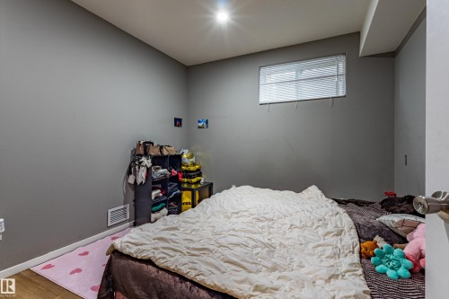 Room featuring light gray walls, wood-finish flooring, and a single window with horizontal blinds - 195 Kulawy Drive, Edmonton, AB - Indoor Photo Showing Bedroom