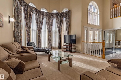 Vaulted living space featuring arched windows, light-toned carpeting, and a second-story interior balcony with wood balusters - 195 Kulawy Drive, Edmonton, AB - Indoor Photo Showing Other Room