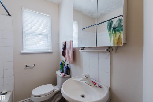 Bathroom featuring a wall-mounted sink, toilet, and a medicine cabinet with mirror doors - 12223 127 Street, Edmonton, AB - Indoor Photo Showing Bathroom